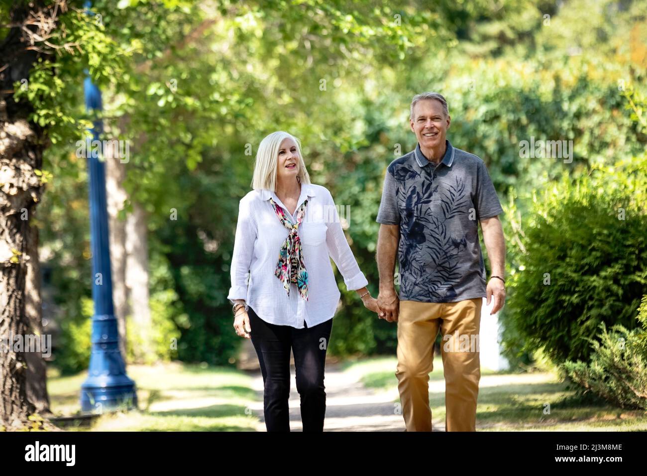Mature couple holding hands while walking outdoors on a park trail; Edmonton, Alberta, Canada Stock Photo