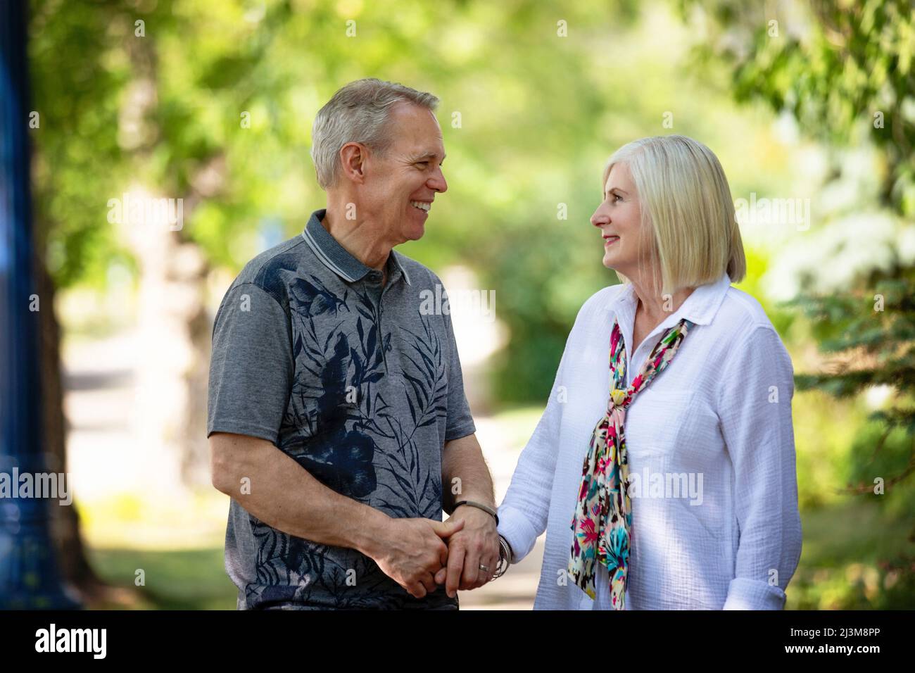 Mature couple holding hands and sharing a moment together while walking outdoors on a park trail; Edmonton, Alberta, Canada Stock Photo