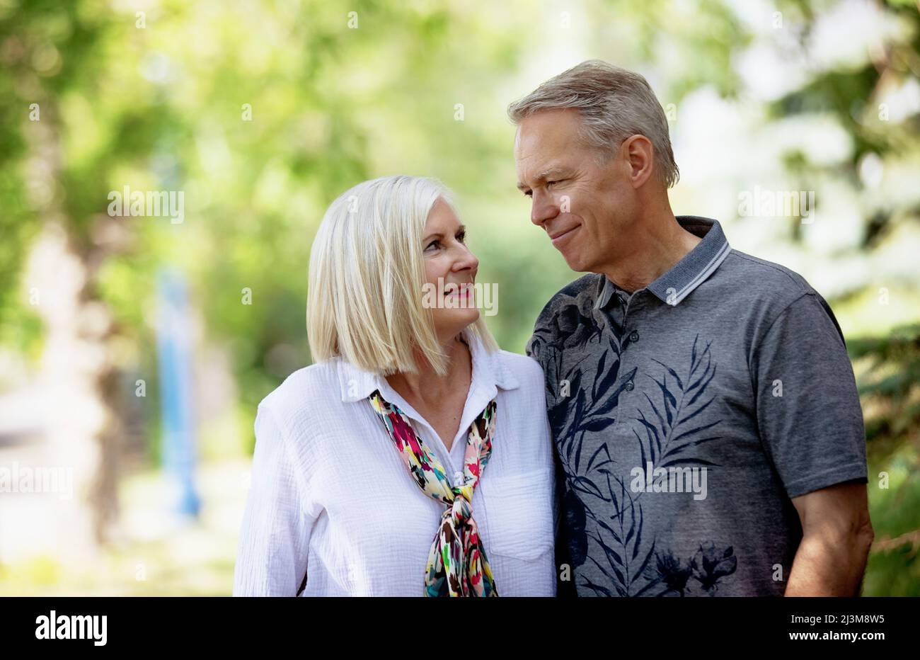 Outdoor portrait of a mature couple in a park as they stand and look at each other; Edmonton, Alberta, Canada Stock Photo