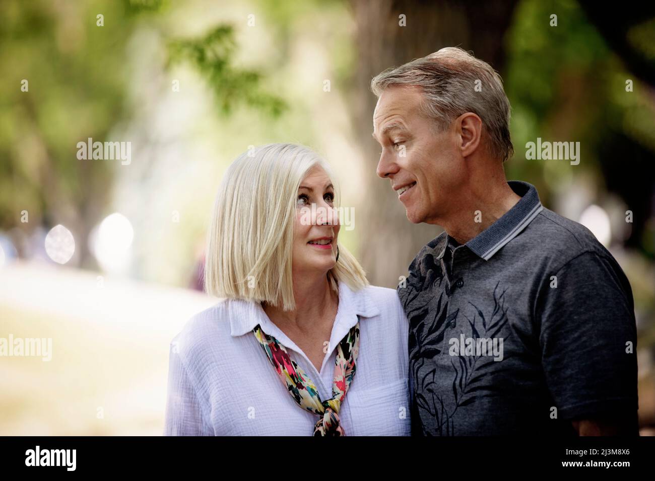 Outdoor portrait of a mature couple in a park as they stand and look at each other; Edmonton, Alberta, Canada Stock Photo