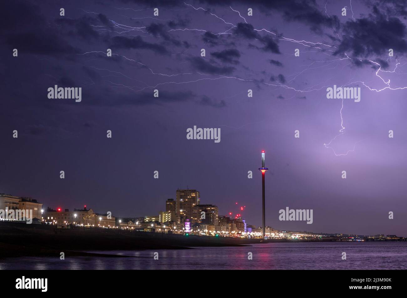 A dramatic bolt of lightning strikes lights up the sky over the  city of Brighton on a stormy summer's night on the south coast of the UK Stock Photo