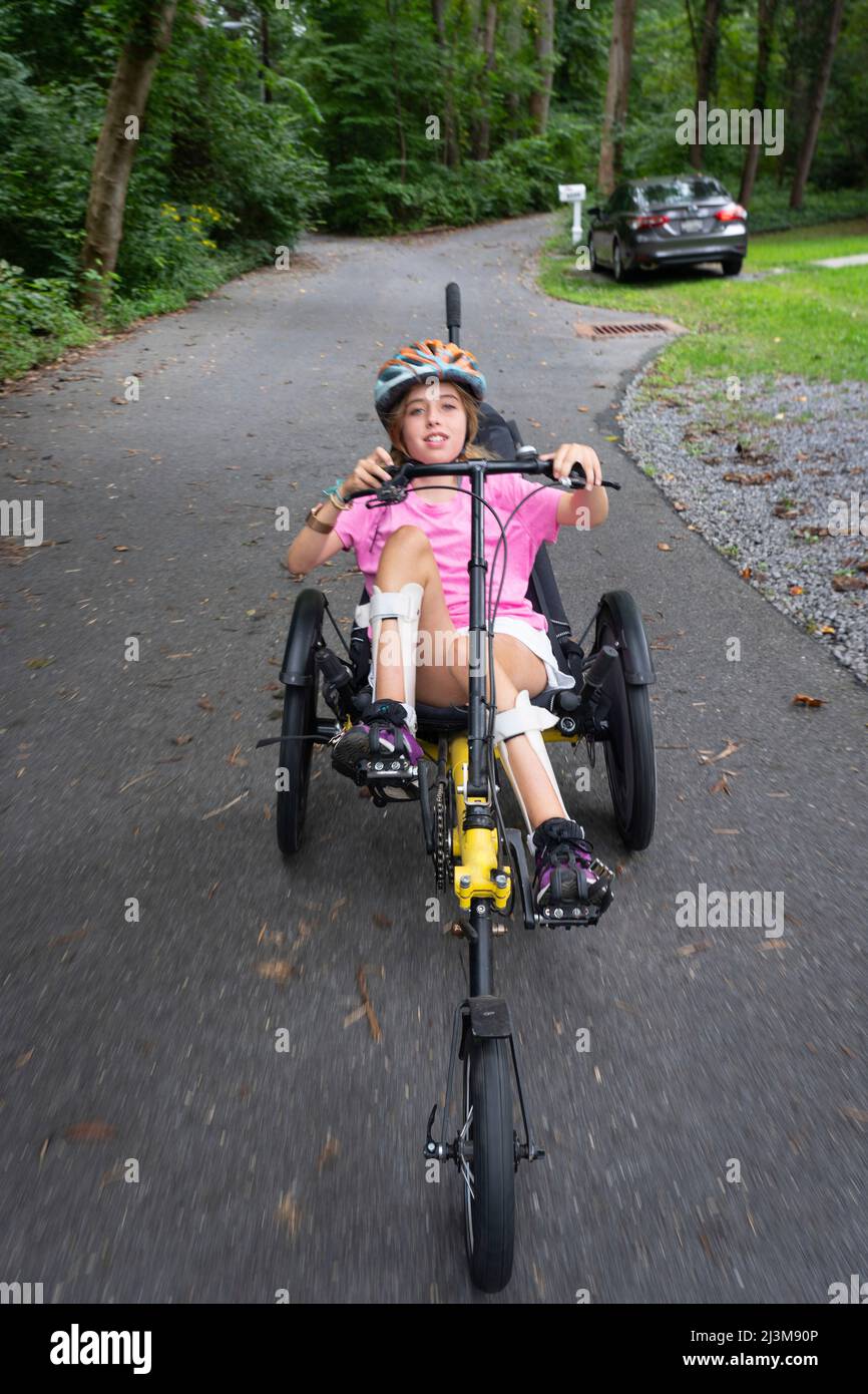 Girl with Ullrich Congenital Muscular Dystrophy riding her recumbent trike bicycle on the street