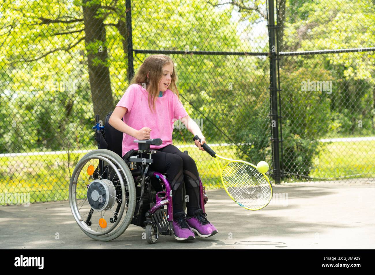 Girl with Ullrich Congenital Muscular Dystrophy plays tennis in her wheelchair; Cabin John, Maryland, United States of America Stock Photo