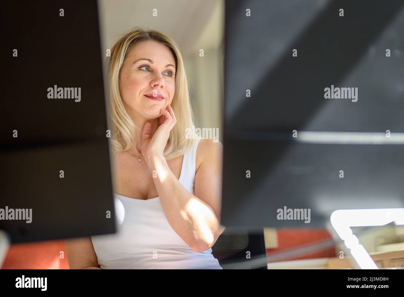 Thoughtful female business person thinking and looking away while working and daydreaming in home office Stock Photo
