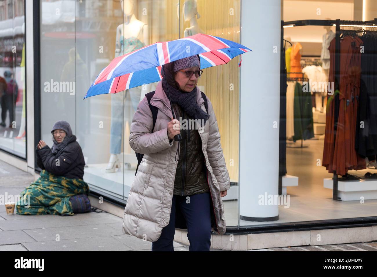 Weather is seen to be relatively dry this morning in London with occasional drizzles as morning commuters pass by Tottenham Court Road and Oxford Circ Stock Photo