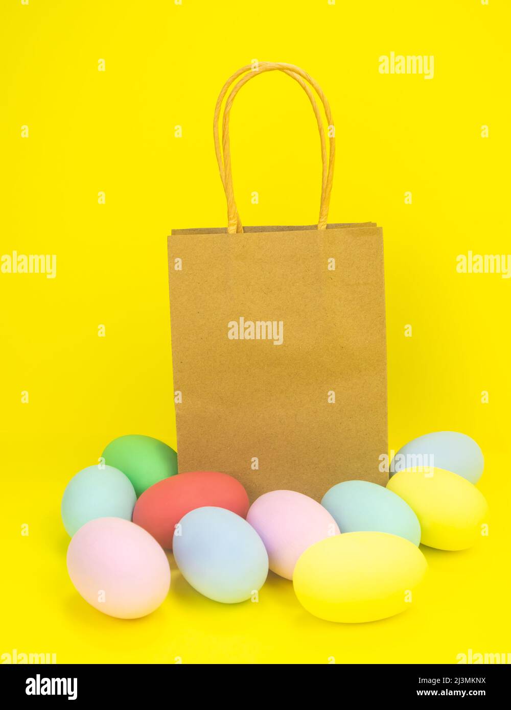 Paper bag on yellow background and easter eggs . Copy space Stock Photo
