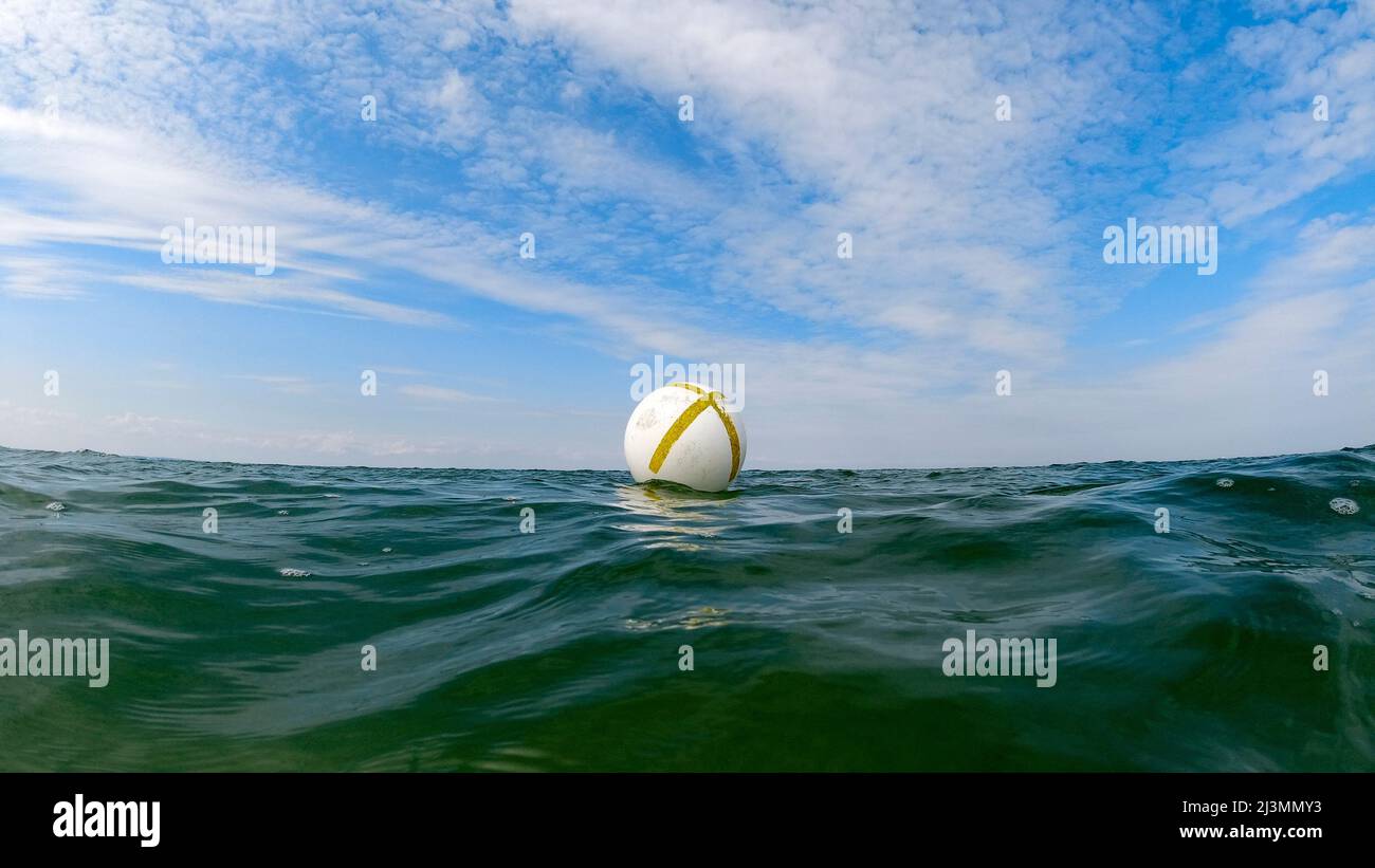Buoy in the sea with blue sky and interesting clouds Stock Photo