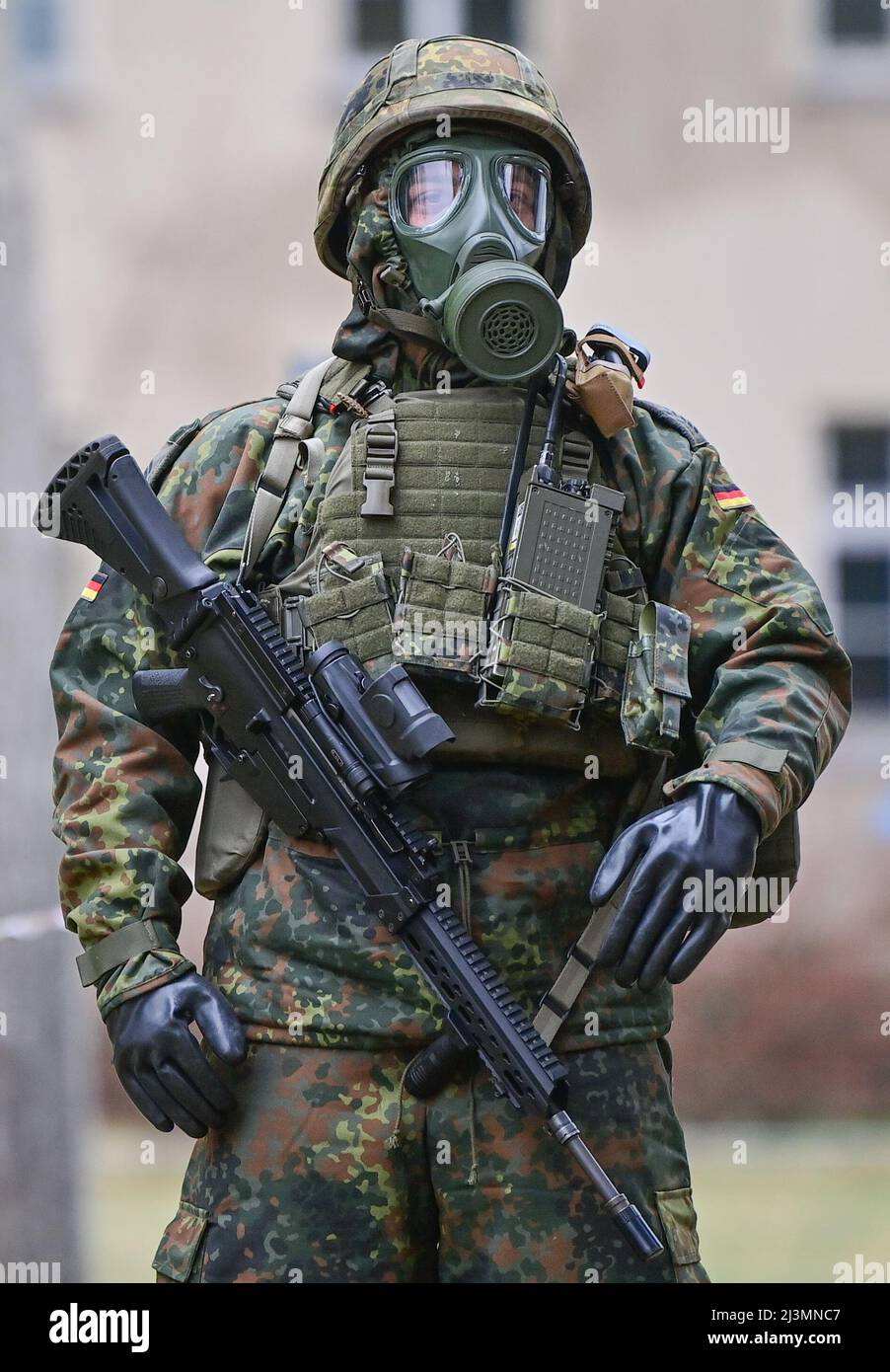06 April 2022, Brandenburg, Strausberg: A soldier of the German Armed  Forces wears a gas mask, protective equipment and a Heckler and Koch G36  assault rifle on the sidelines of the ceremonial