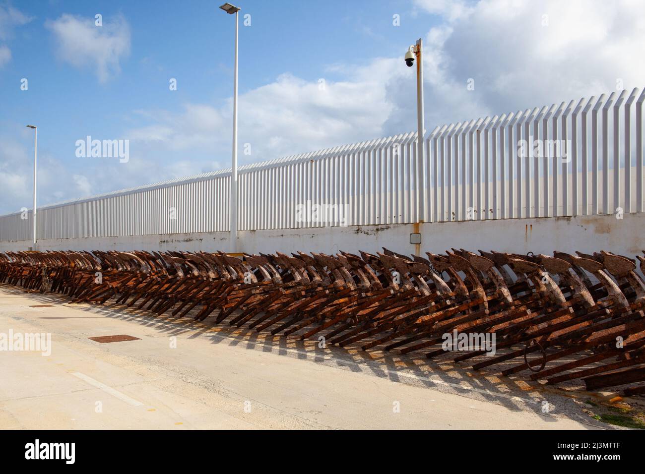 A long line of discarded and rusty anchors in Tarifa harbor, Andalucia, Spain Stock Photo