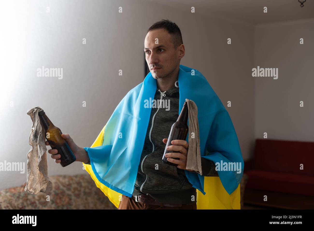 man with flag of ukraine with molotov cocktail in room Stock Photo