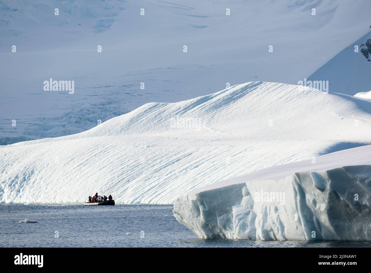 Afternoon light, tourists in a Zodiac observe the scenery around Marguerite Bay, south of Antarctic Circle.  Antarctica, Stock Photo