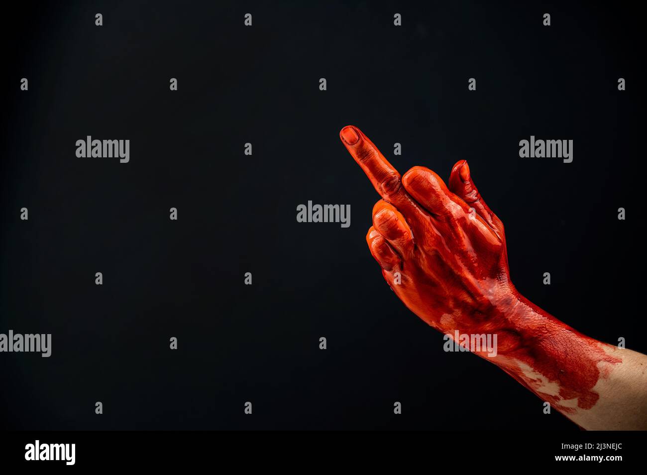 Female hand stained with blood shows the middle finger on a black background.  Stock Photo