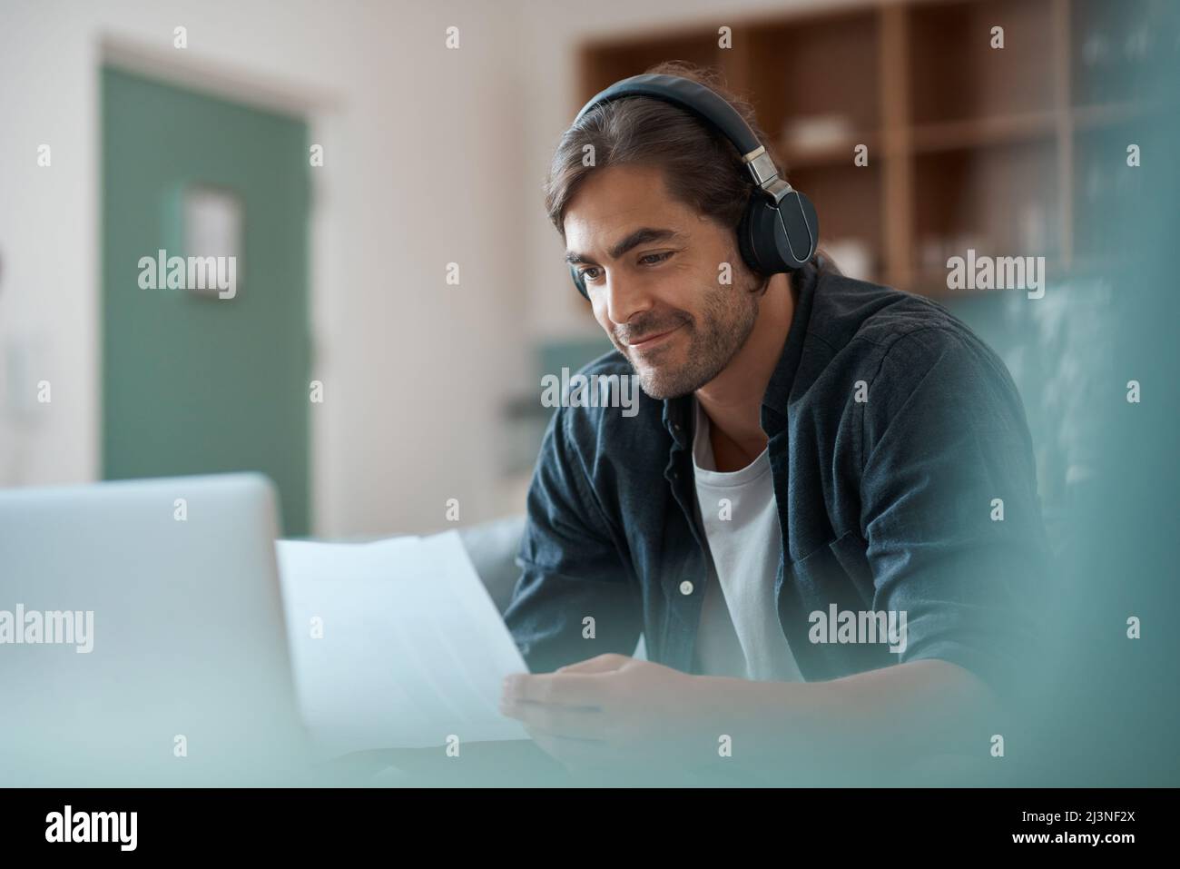 Seeing my ideas on paper. Shot of a young man doing paperwork while using a laptop at home. Stock Photo