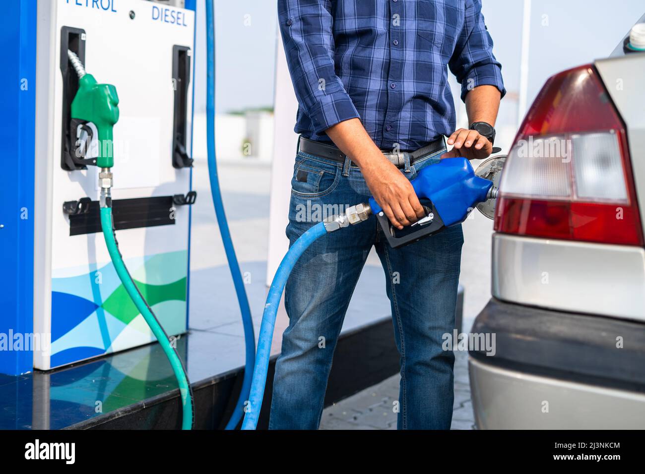 young man self refueling car at petrol or gas filling station after paying from mobile - concept of transportation, vocation and traveling. Stock Photo