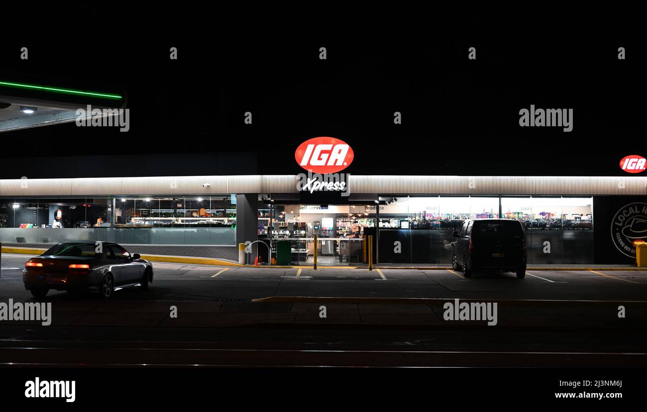 Illuminated IGA Xpress convenience store at night, as a car approaches