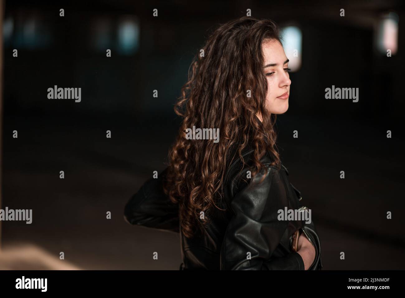 Portrait of a beautiful teen brunette girl in leather jacket, back view. Copy space Stock Photo