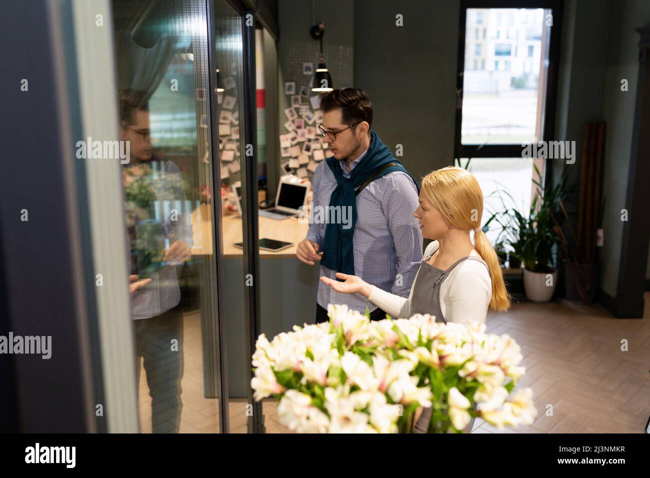flower shop employee next to a refrigerator with fresh flowers for