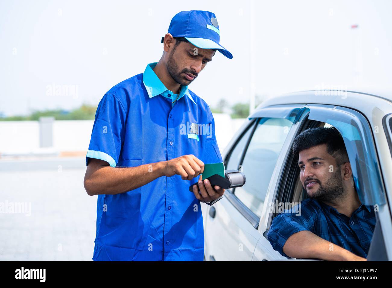 Customer doding payement using creadit card at petrol pump or gas filing station - concept of cashless transaction, technology and small business. Stock Photo