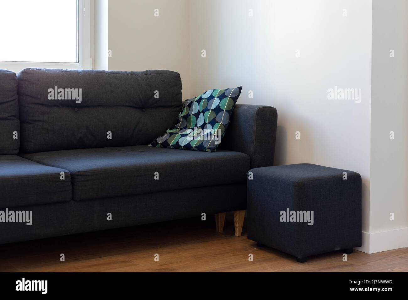 Dark blue sofa with blue and turquoise cushion in a white room Stock Photo