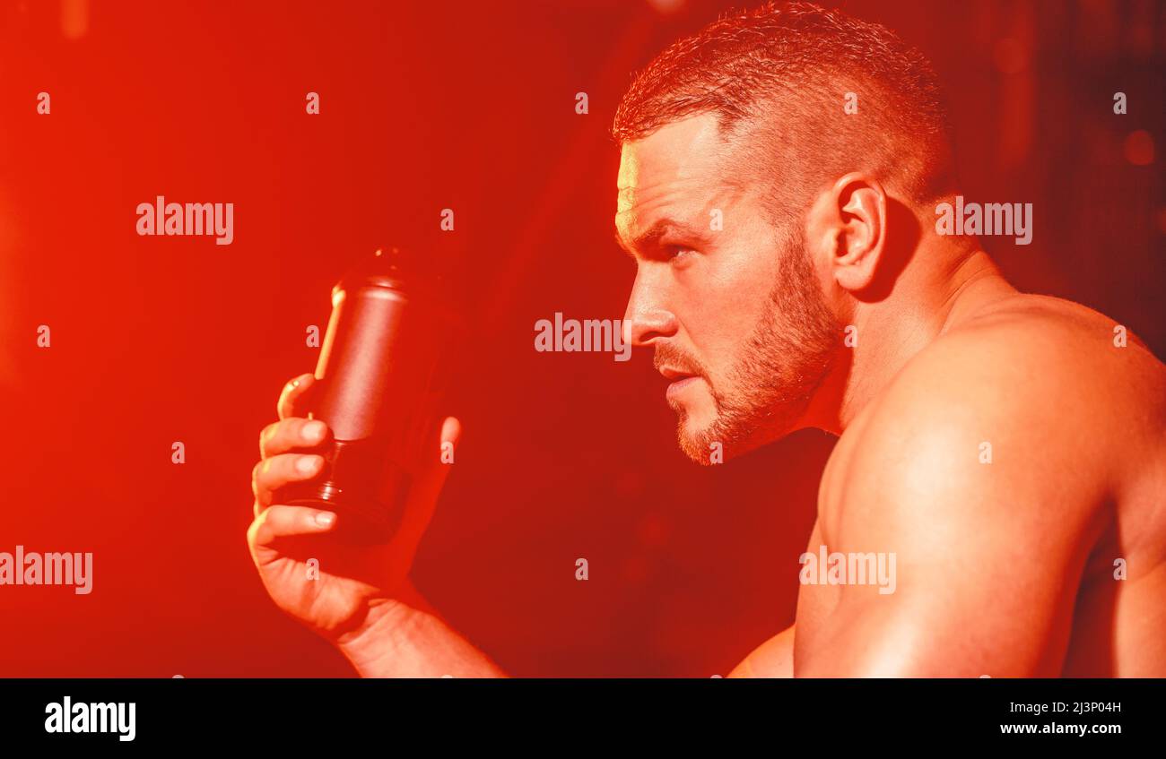 Young man drinks water in the gym. Man at gym and holding bottle of ...