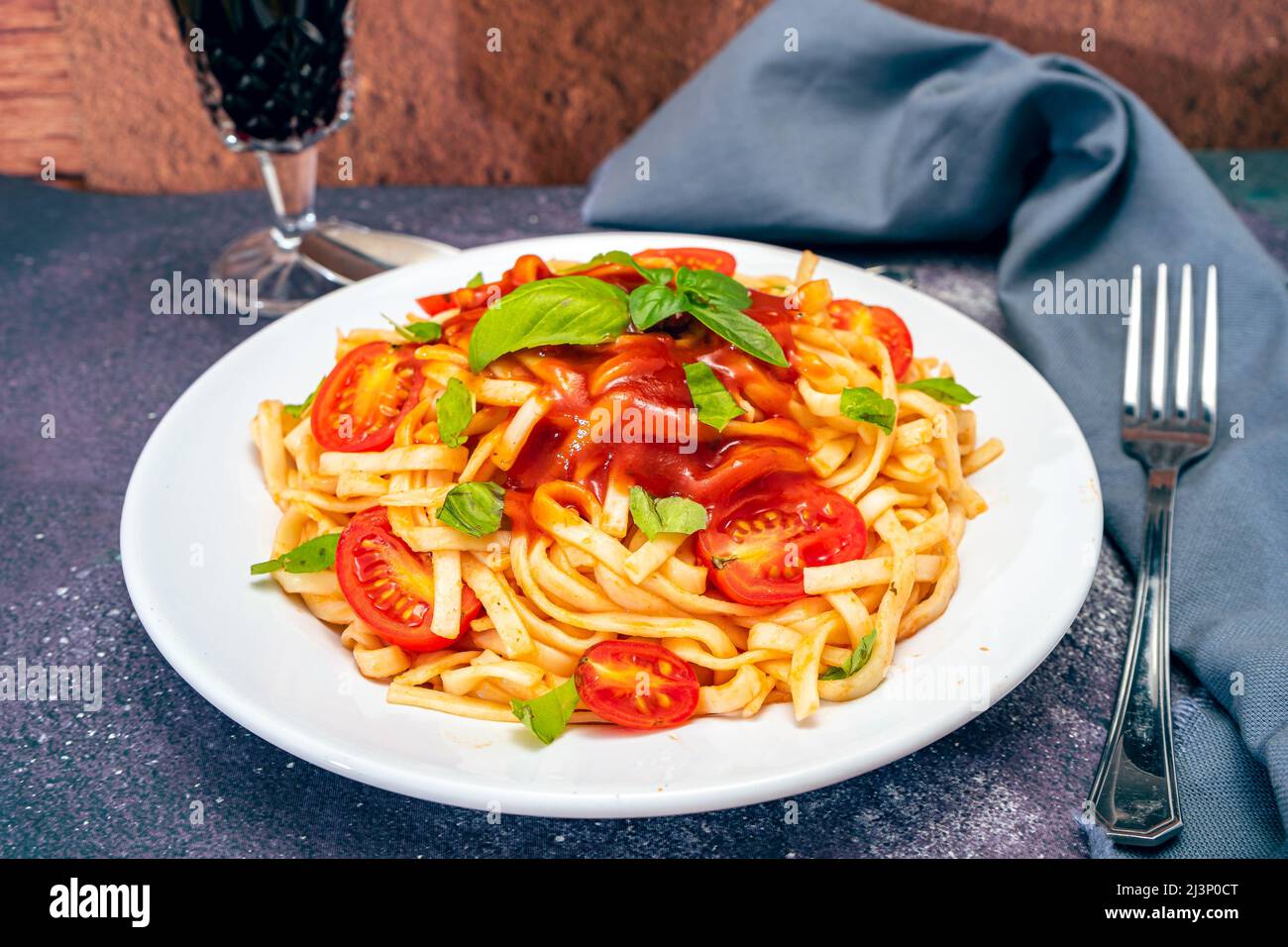 High view of a plate of spaghetti pasta with a delicious tomato sauce with homemade basil leaves. Homemade and natural food concept. Stock Photo