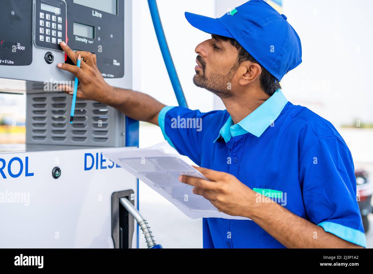 Petrol pump worker noting or writing fule meter at petroleum station - concept of employment, jobs and gas filling station. Stock Photo