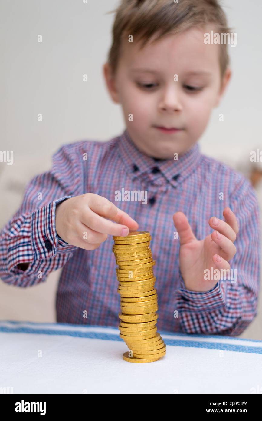 Tower of coins. A little boy builds a column of gold coins Stock Photo