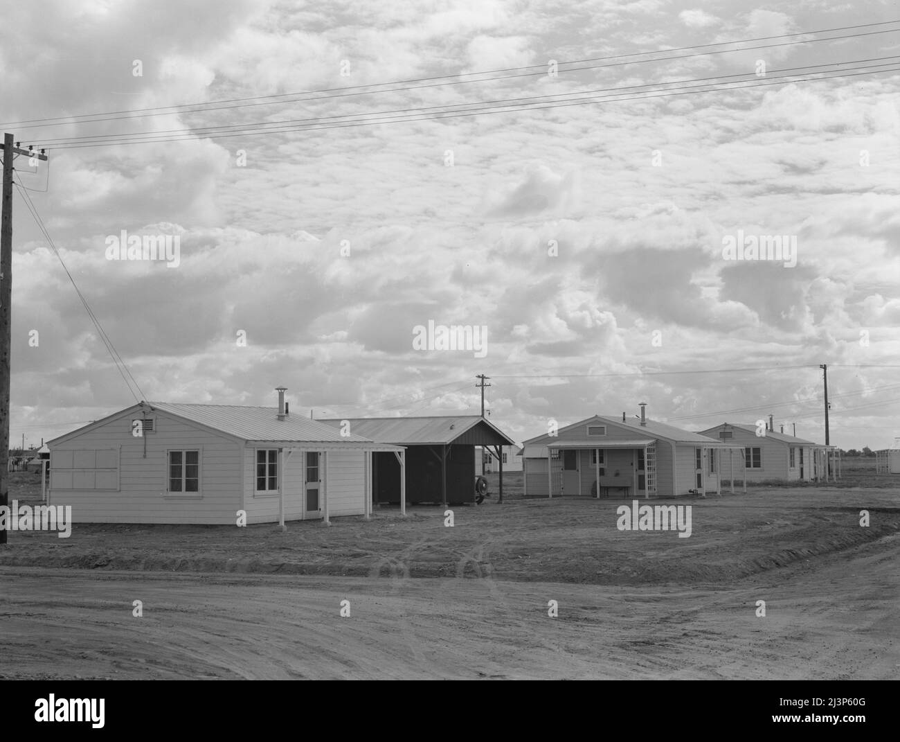 Looking from the camp to adjoining tract where Farm Security Administration (FSA) has just completed forty homes to be occupied by low income workers. These homes represent a first step in stabilization of this group. Rent is eight dollars and twenty cents monthly, which includes gas and electricity. Shafter migrant camp, California. Stock Photo