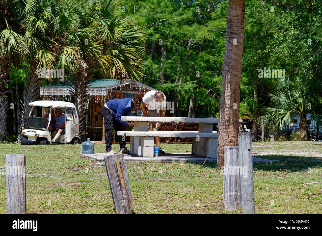 2 workers painting stone picnic table, job, maintenance, golf cart