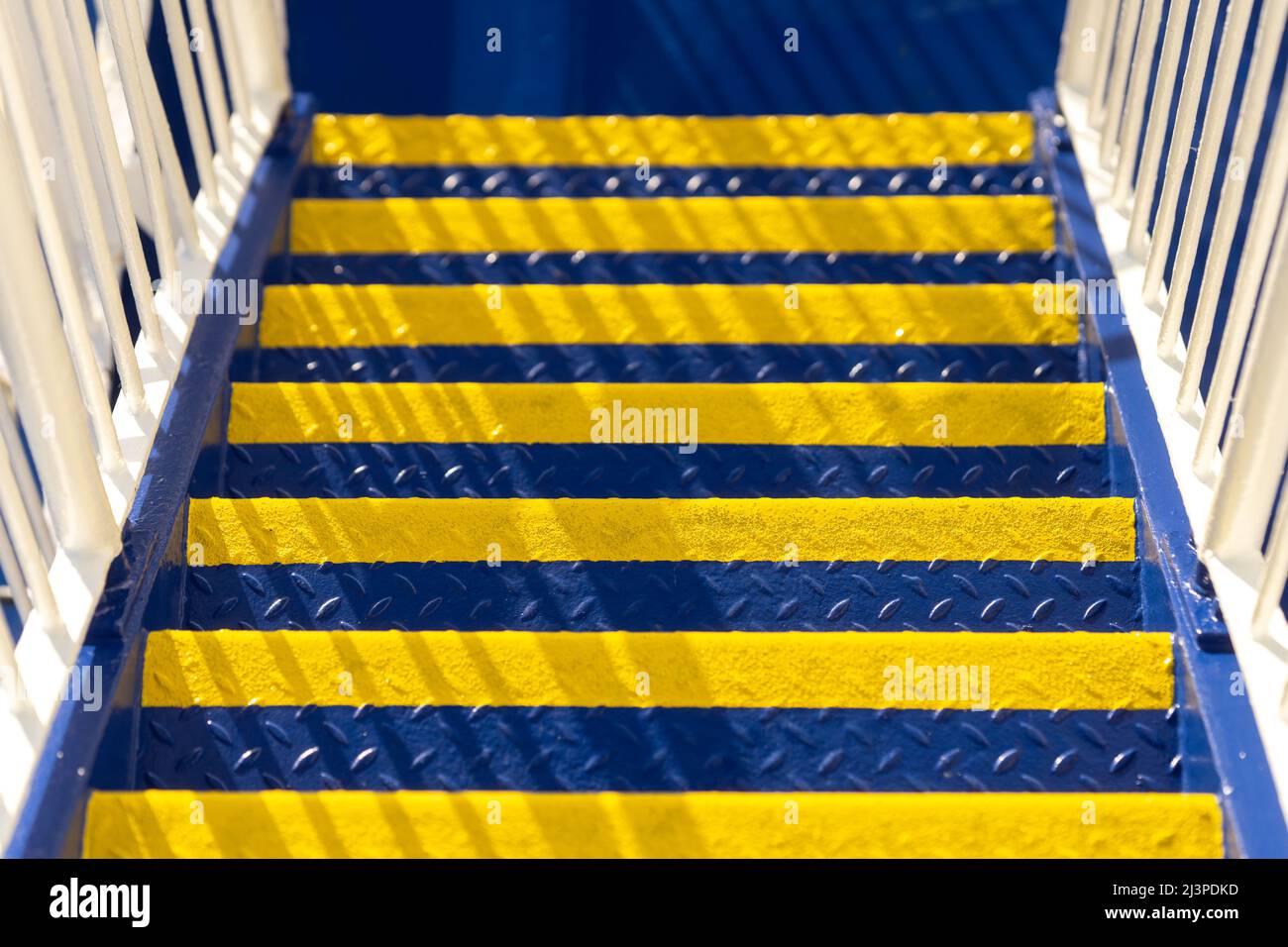 Industrial stairway newly painted in bright yellow and rich blue Ukrainian flag colours on sunny day. Colours of Ukraine. Stock Photo