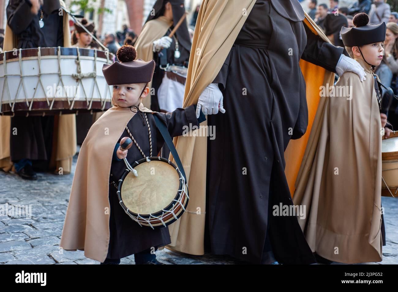A little child is seen holding a drum. In Spain, Holy Week is called 'Semana  Santa' and it's celebrated with unrivaled pageantry and emotion. It comes  with religious processions around the country