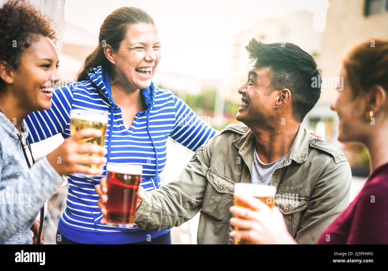 Multicultural friends drinking and toasting beer pints at brewery bar garden out side - Beverage life style concept with men and women having fun Stock Photo
