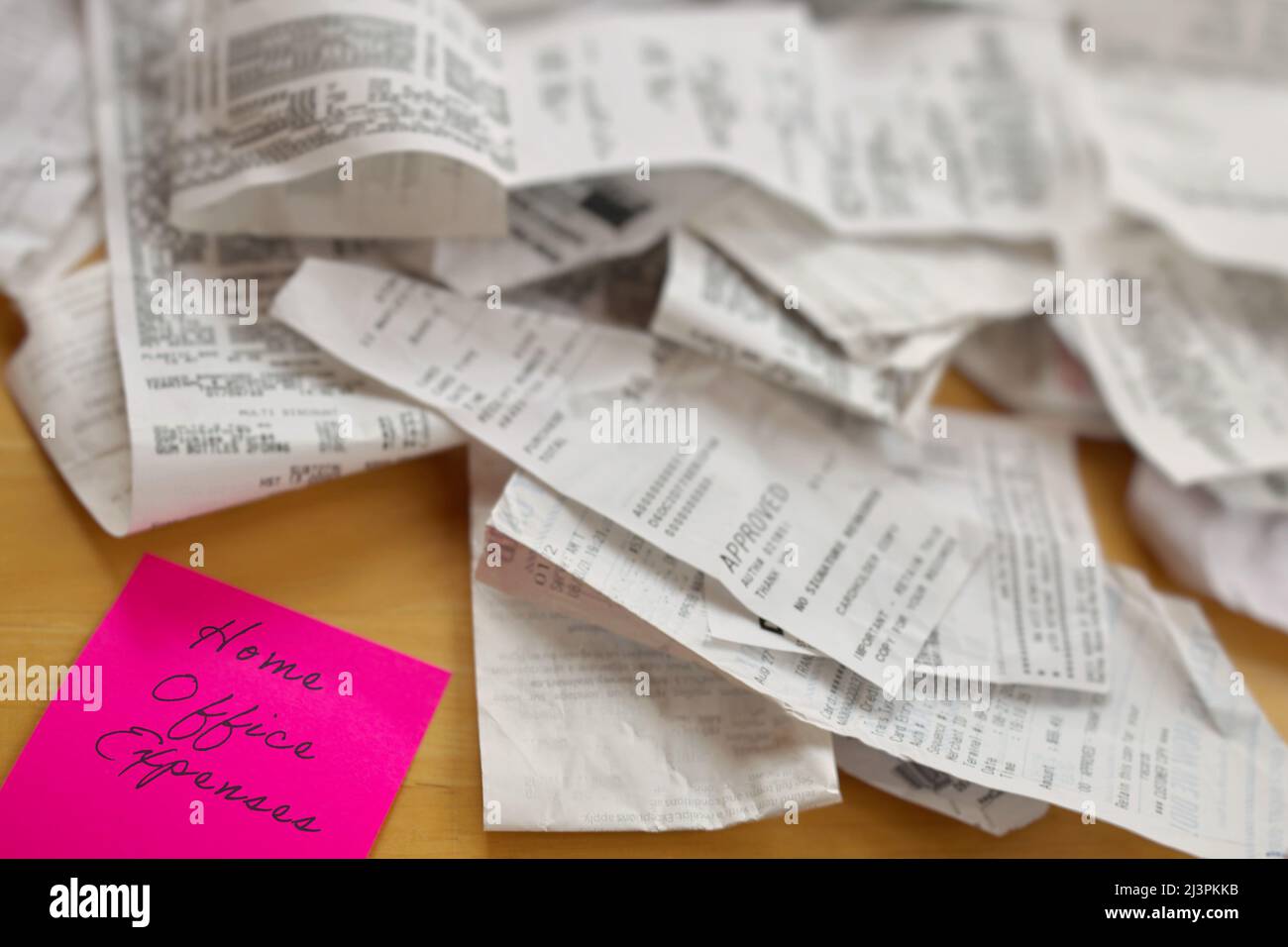 High Angle View of Pile of Receipts with Home Office Expenses Pink Sticky Note on Table Stock Photo