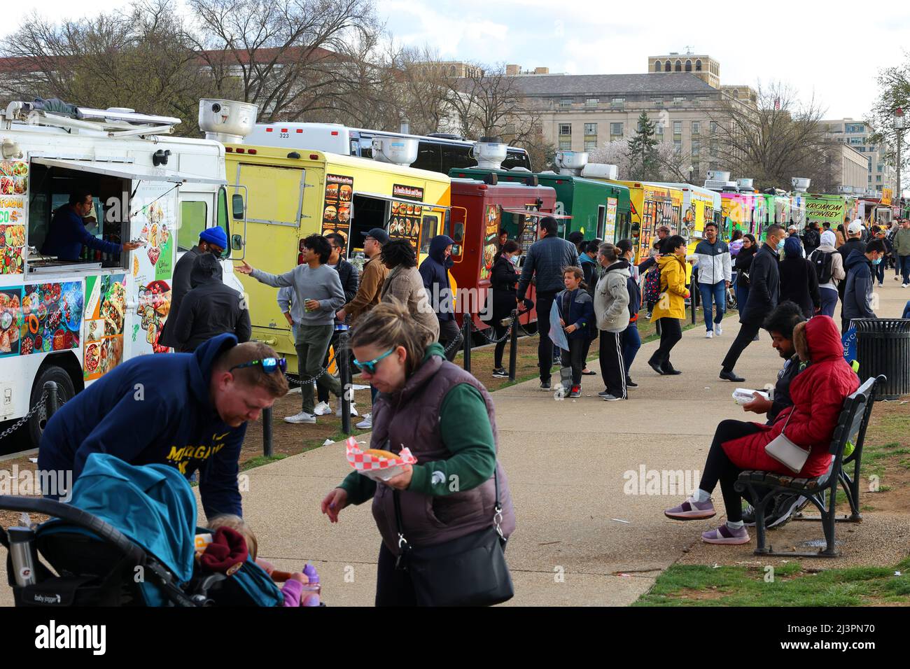 People eating, and buying food from dozens of food trucks lined along the National Mall, 7th St NW, Washington DC. Stock Photo