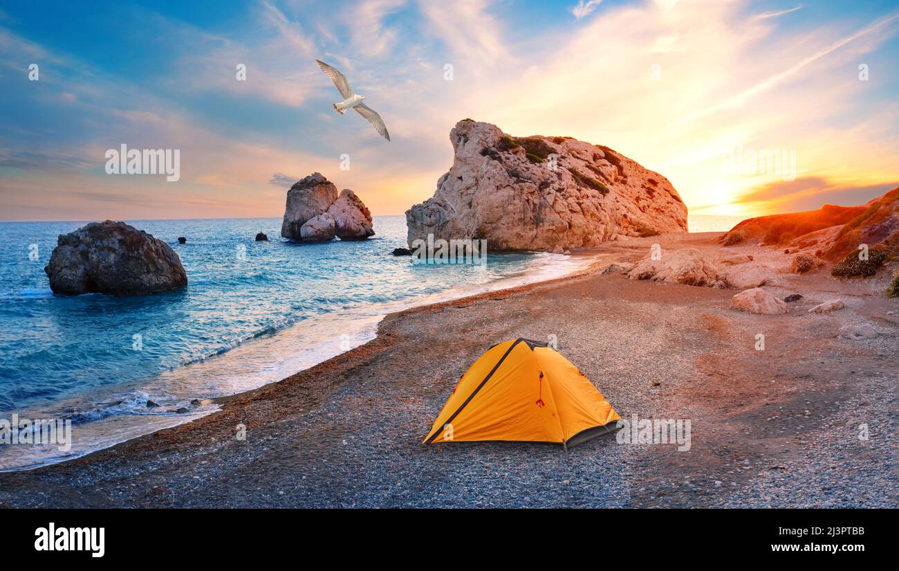 Orange tourist tent on beach of Aphrodite in Cyprusand seagull in sky Stock Photo
