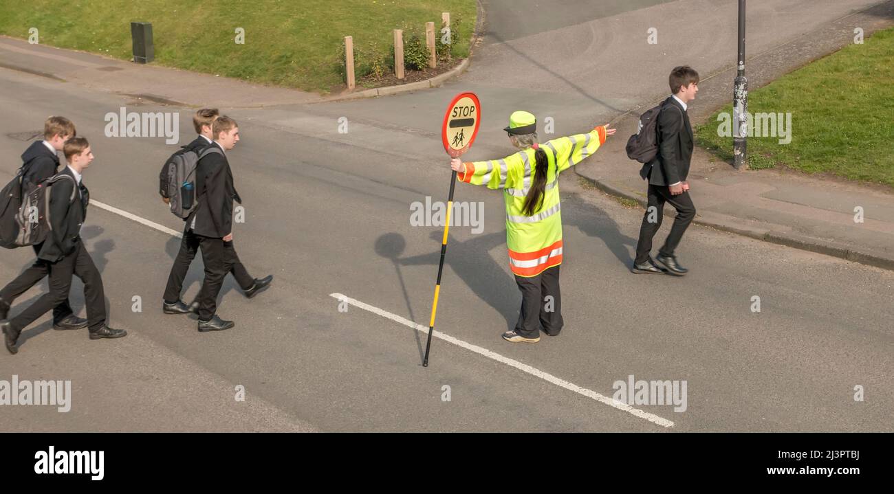 Lollipop Lady and school students crossing road England, UK Stock Photo