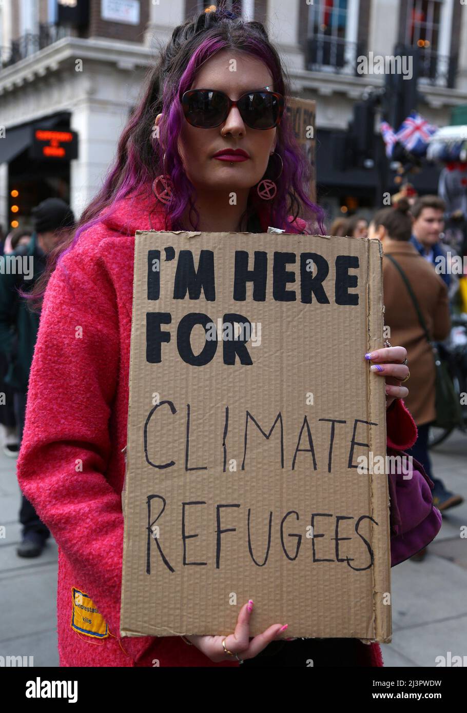 An Extinction rebellion protester olds a sign that reads 'I'm here for climate refugees'. the theme of the opening march for the week of climate activism is a statement on why you are protesting. London. 9th April 2022. Anna Hatfield/Pathos Stock Photo