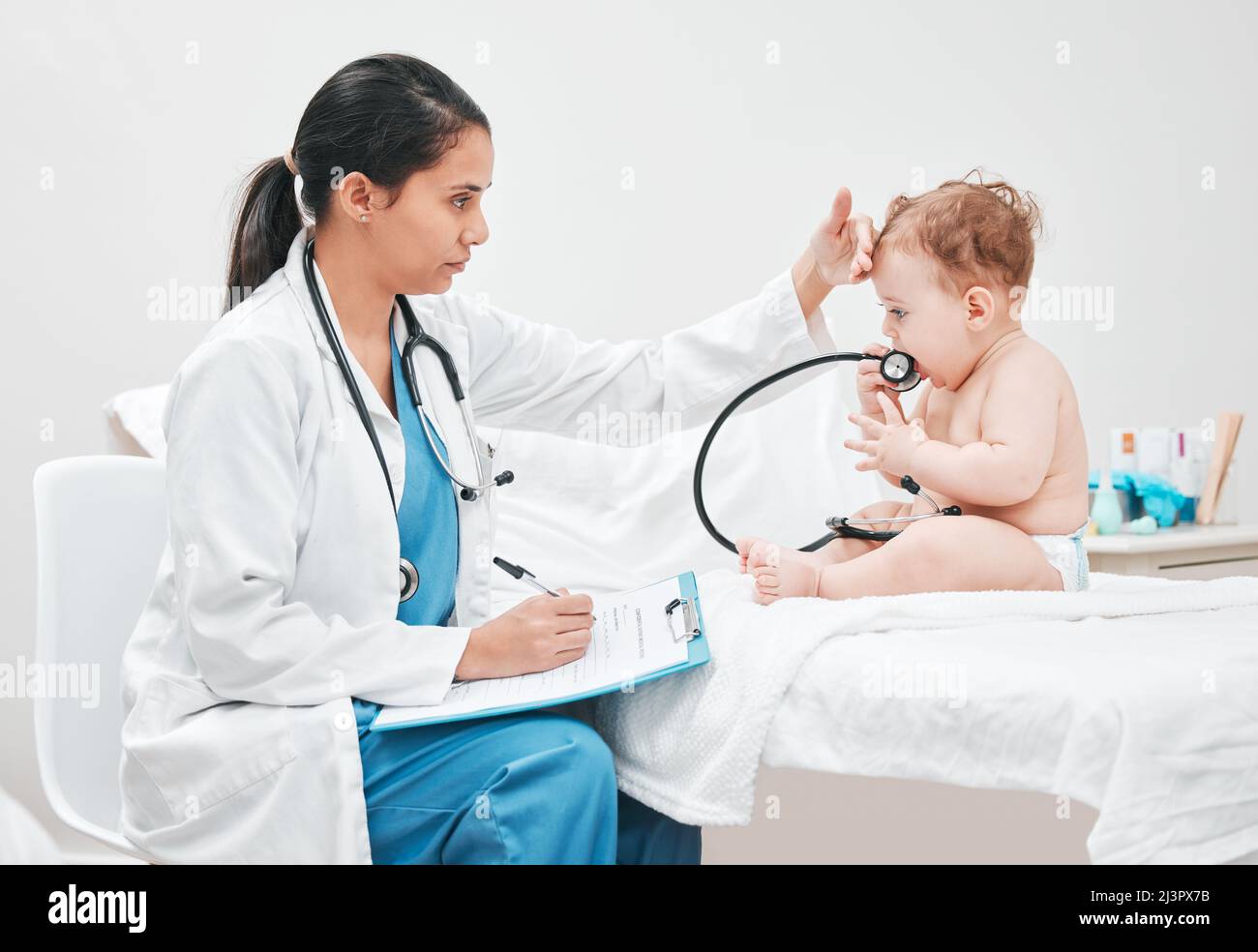 Its normal for babies to have a fever when teething. Shot of a paediatrician completing paperwork during a checkup. Stock Photo
