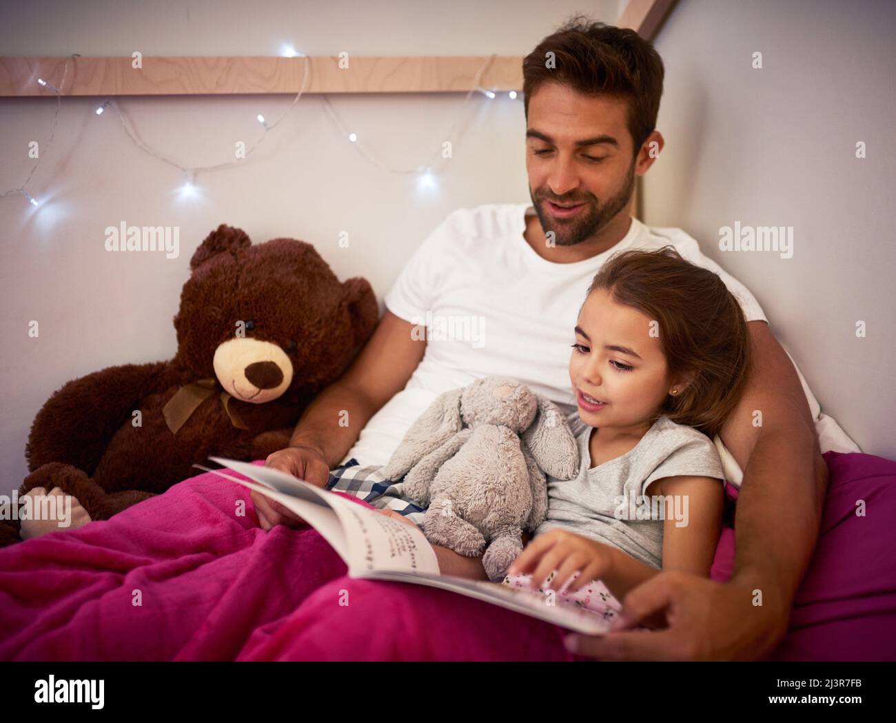 She cant sleep without Dad first reading her a story. Cropped shot of a father reading a book with his little daughter in bed at home. Stock Photo