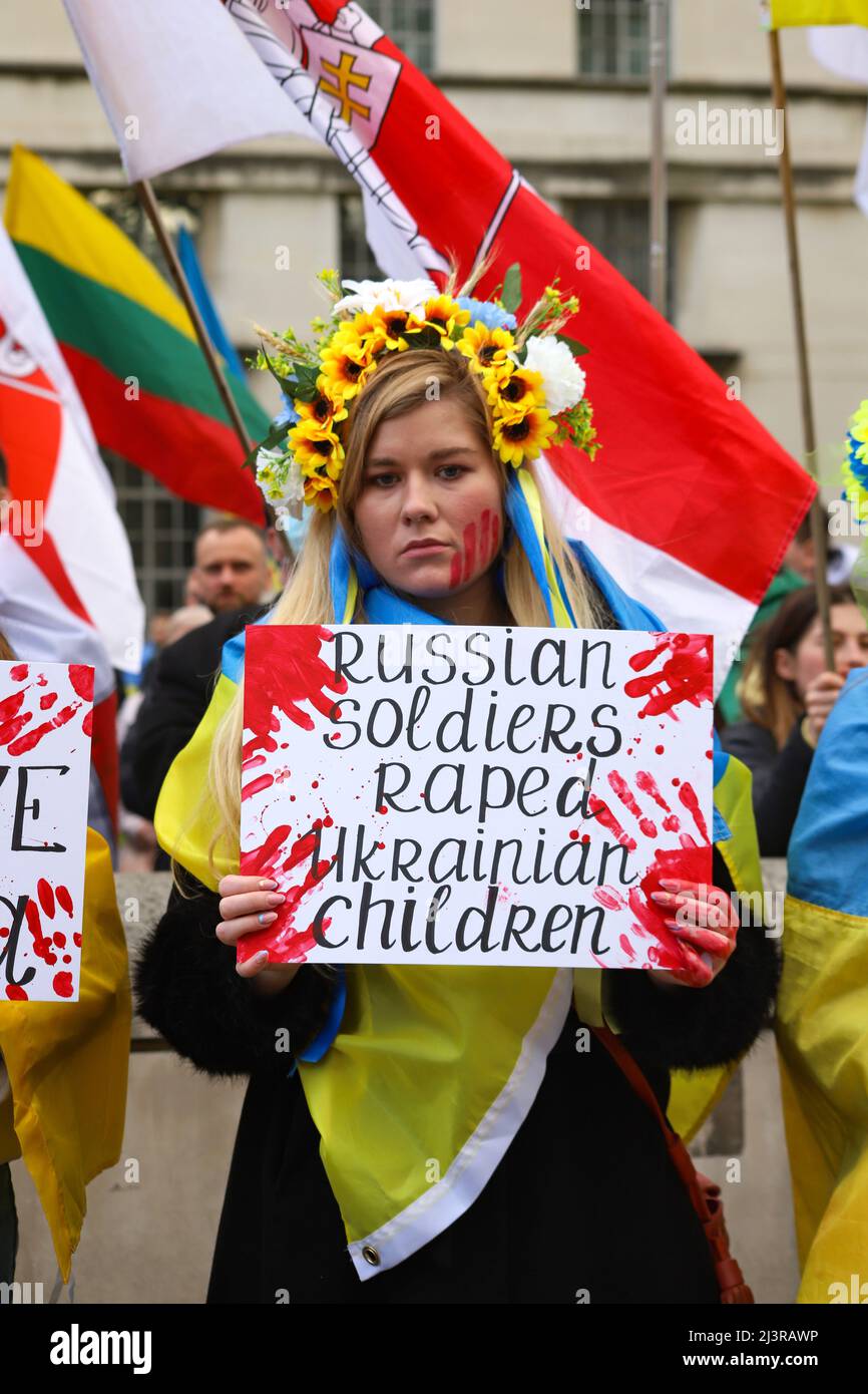 London, England, UK 9 April 2022 Stand with Ukraine protest and die-in at Downing Street. Protesters wore traditional costumes and carried placards with statements concerning crimes committed by Russian soldiers and lay with hands tied and chained. Stock Photo