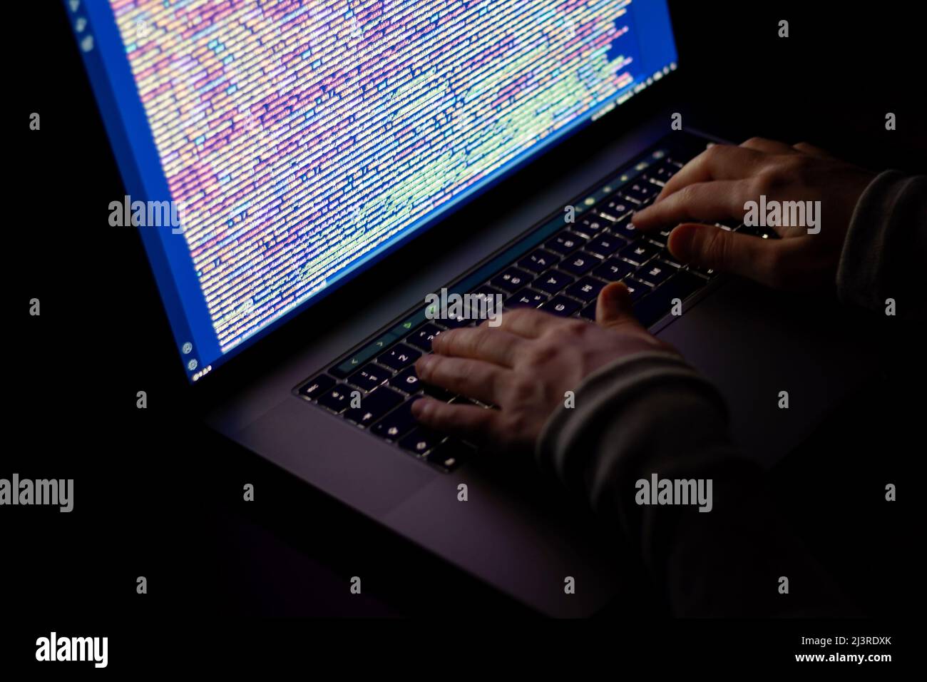 Freelance web developer working at night, programming the web with javascript like a hacker. Close-up hand and computer Stock Photo