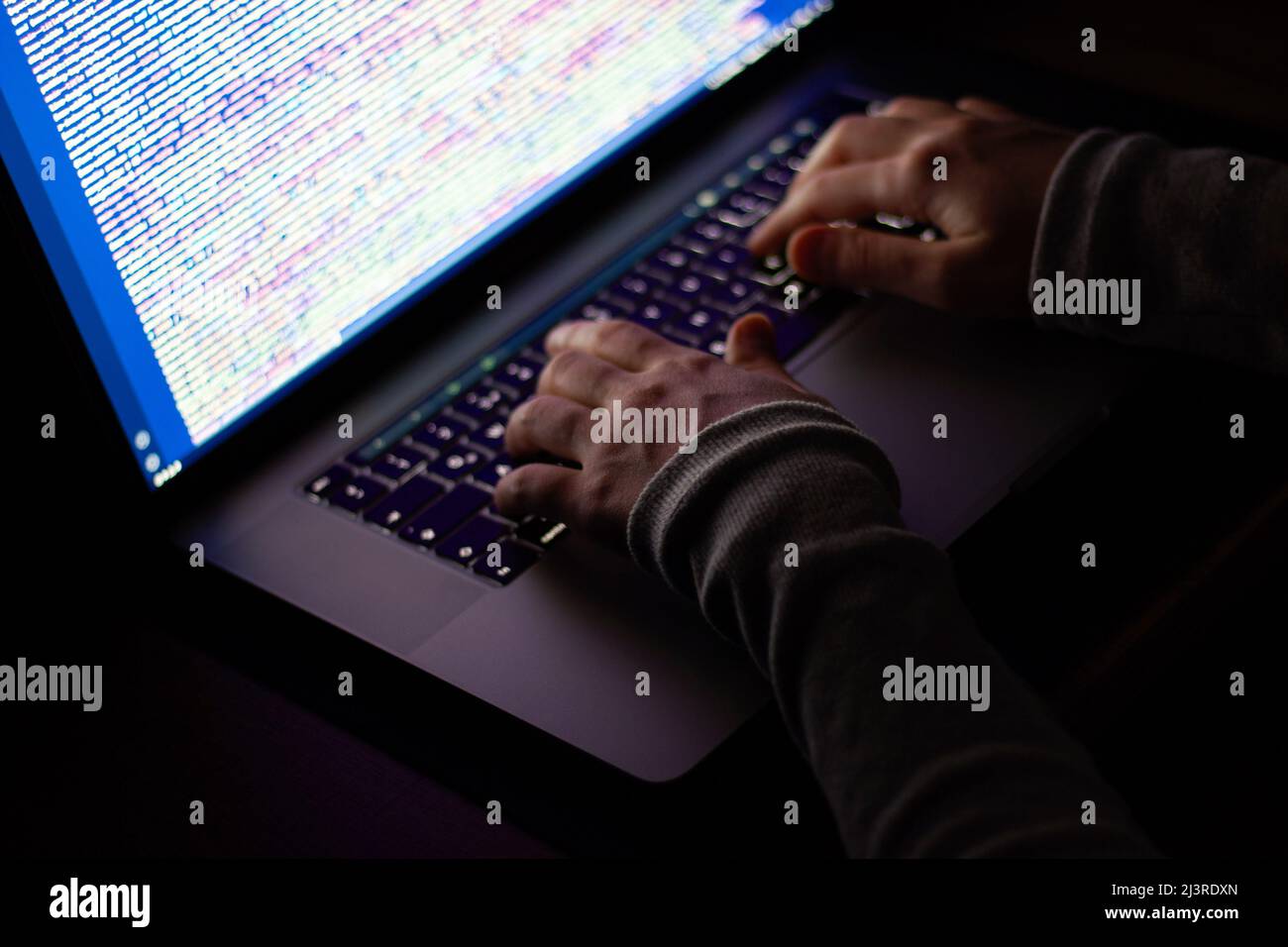 Freelance web developer working at night, programming the web with javascript like a hacker. Close-up hand and computer Stock Photo