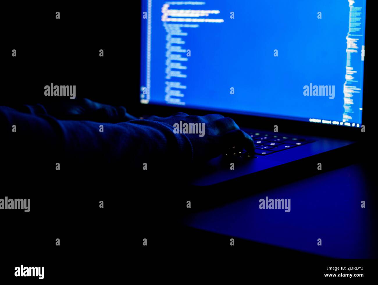 Female freelance developer writes code at night. Blue computer screen and hands on keyboard Stock Photo