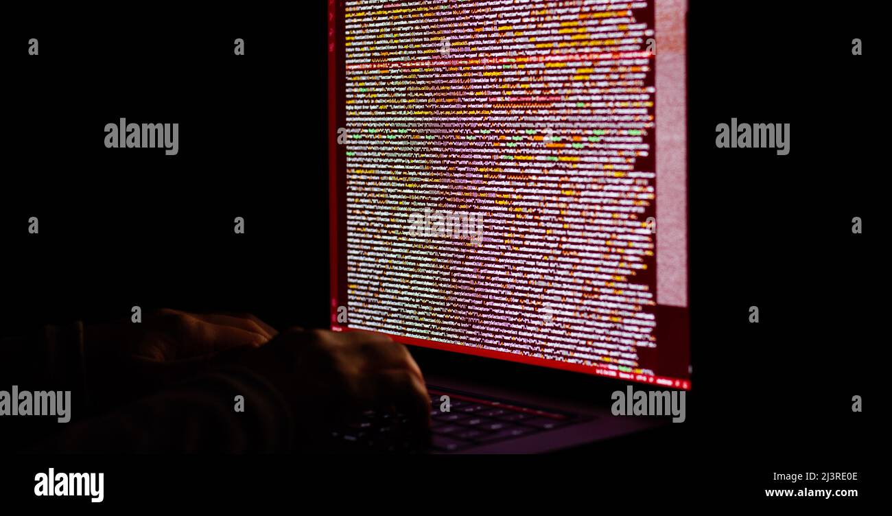Freelance web developer working at night, programming the web with javascript like a hacker. Close-up hand and computer Stock Photo