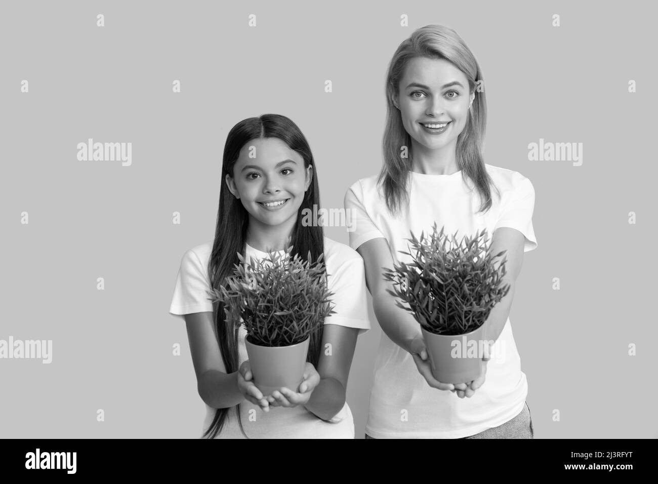 Foster to adopt. Foster family. Adopted daughter and mother hold houseplants. Child adoption Stock Photo