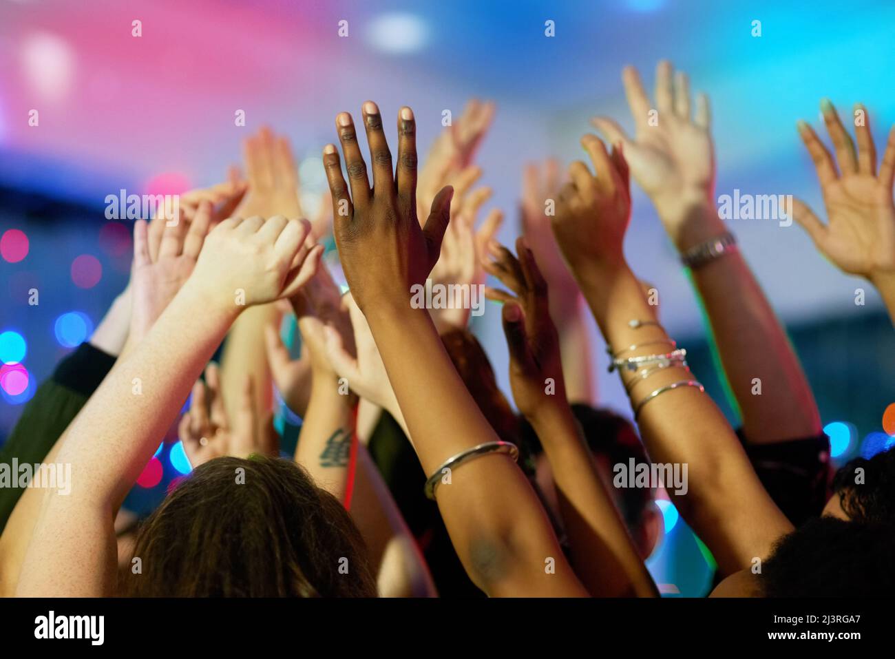 Raise the roof. Shot of a group of friends dancing with their arms raised in a nightclub. Stock Photo