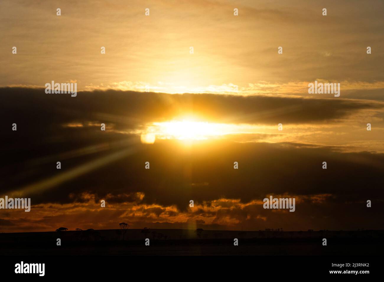 Setting sun behind dark clouds Stock Photo