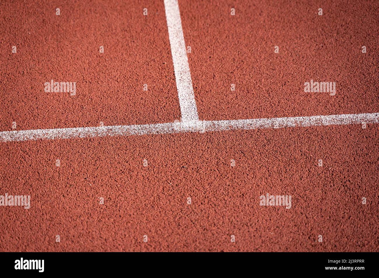 Rubber playground of an outdoor basketball court. White lines on a red synthetic material. A damping polymer is used for the ground material. Stock Photo