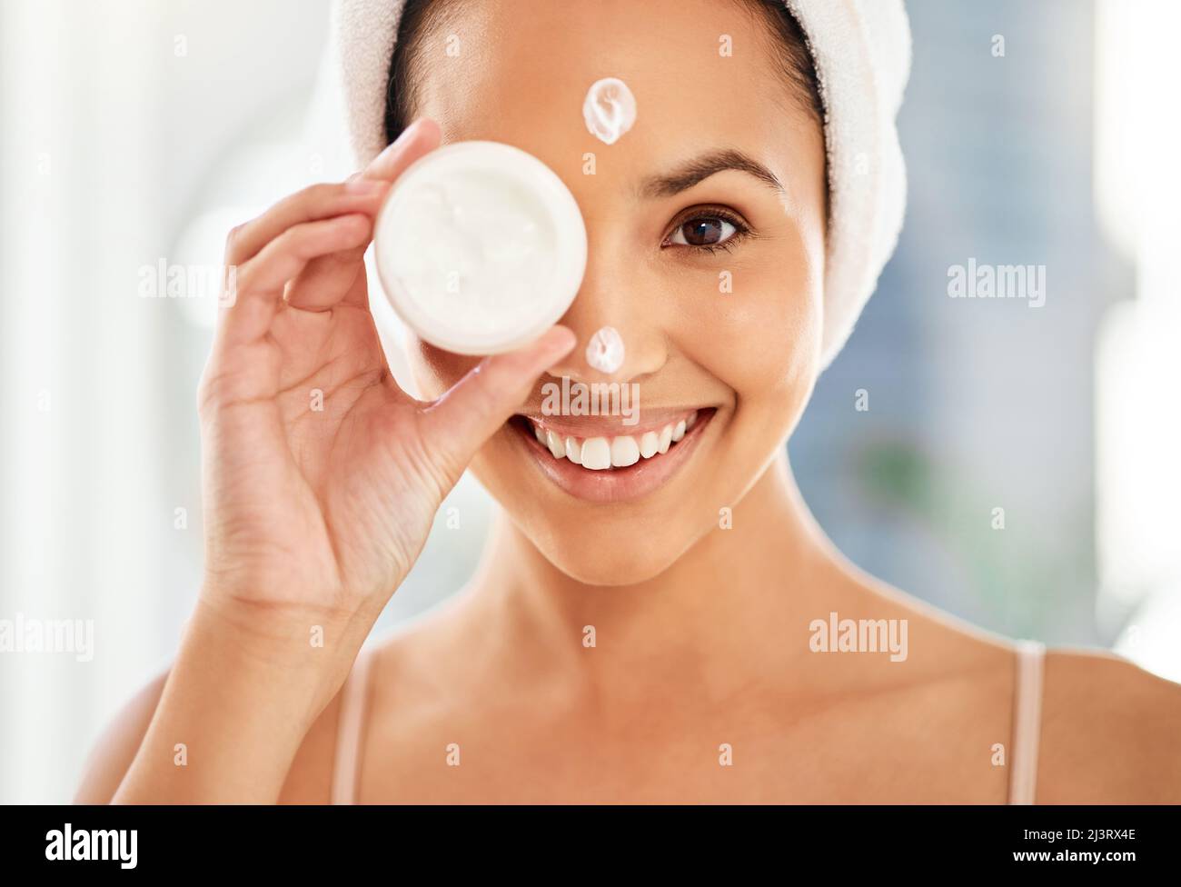 Dont forget to moisturise. Shot of a young woman applying cream to her face at home. Stock Photo