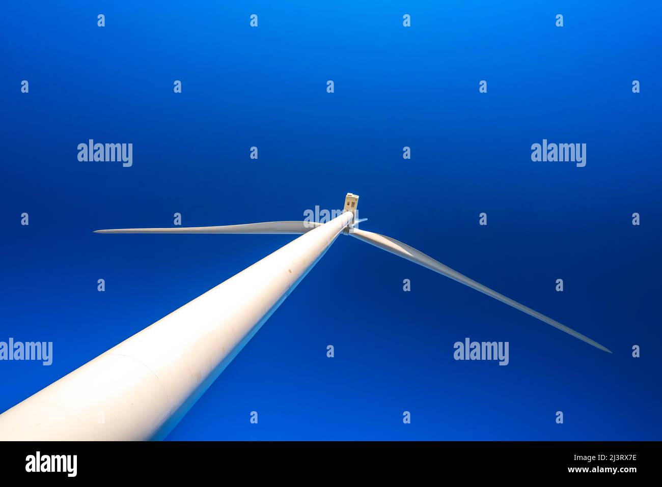 Giant wind turbine seen from below with blue sky background. This is a